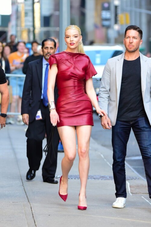 Anya Taylor-Joy brings the heat to the streets of NYC! Her daring red dress leaves little to the imagination, with a plunging neckline showcasing her perky breasts and a high slit teasing her bare ass cheeks. What a bold and beautiful look! 